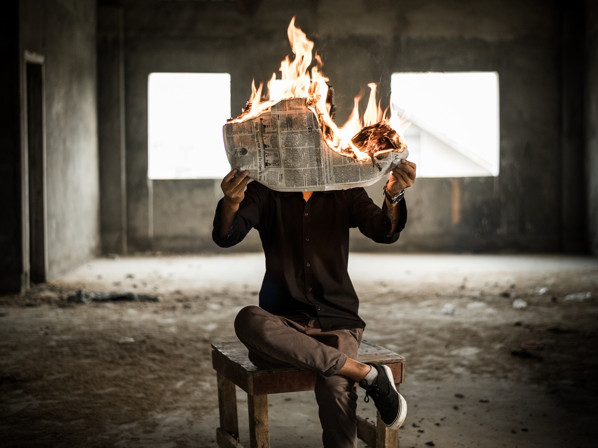 man holding a burning newspaper
