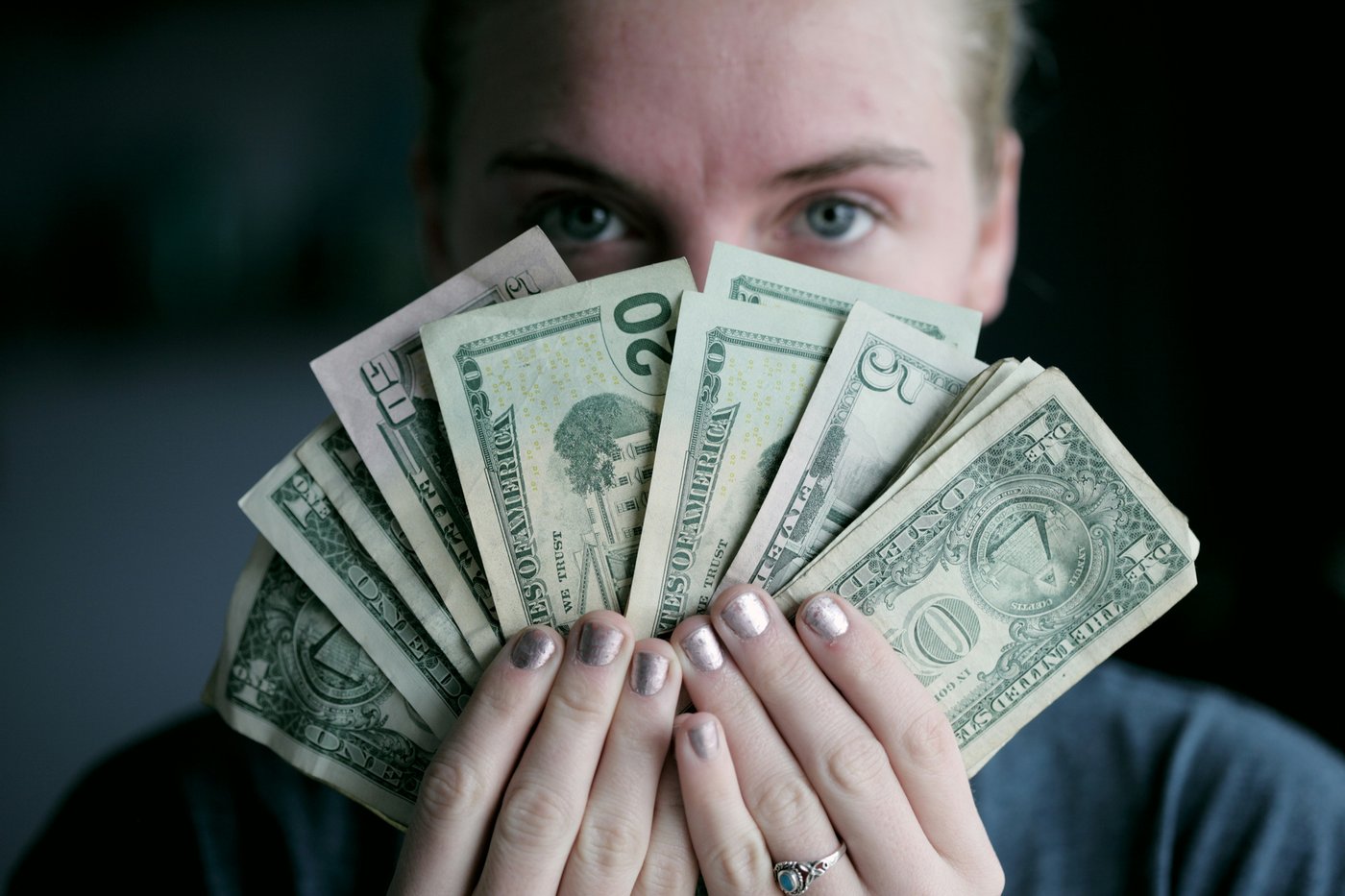 person, indoors, holding a fan full of money