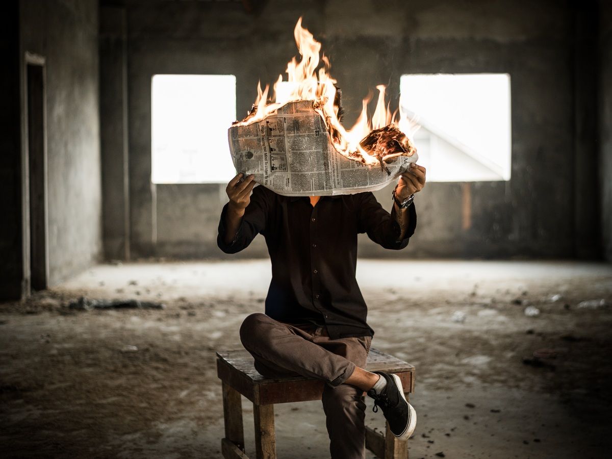 man holding a burning newspaper