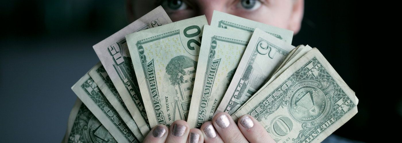 person, indoors, holding a fan full of money