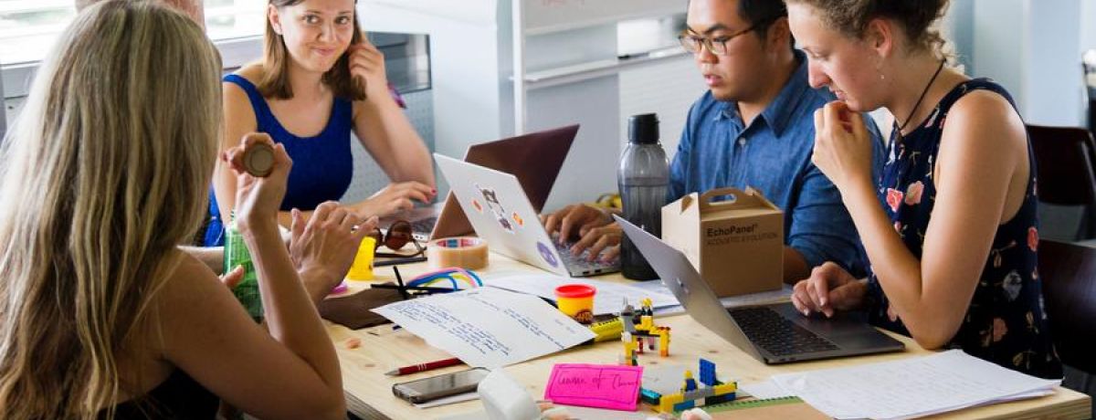 A Team Of People Sitting Around A Table Working