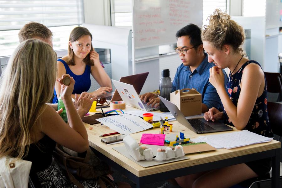 A Team Of People Sitting Around A Table Working