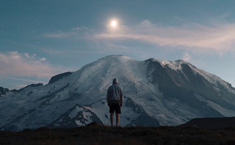 man looking up at mountain