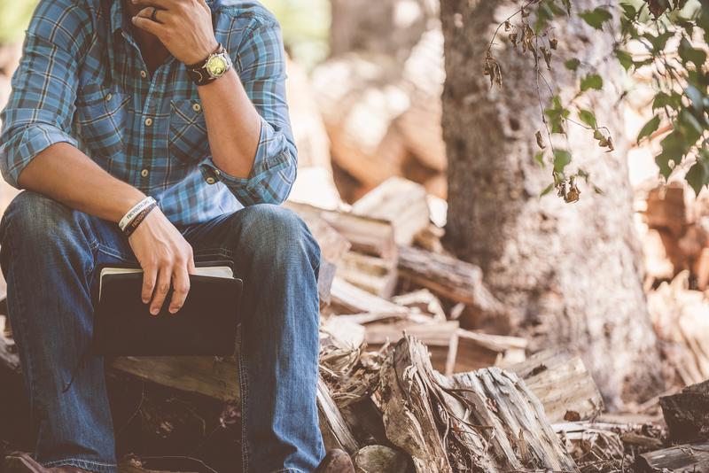 guy sitting on tree with Bible