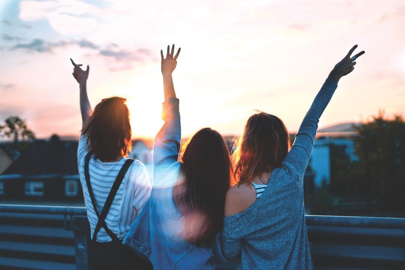 3 woman raising hands sunset