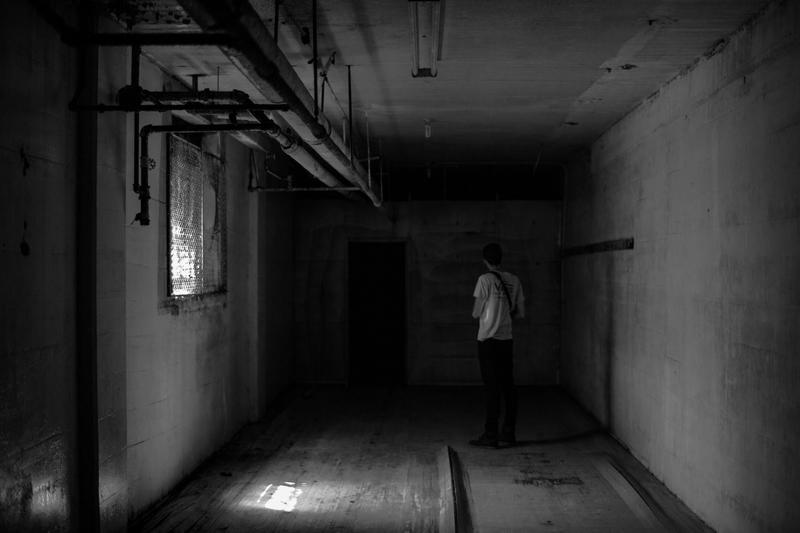 Man facing a dark door in a basement