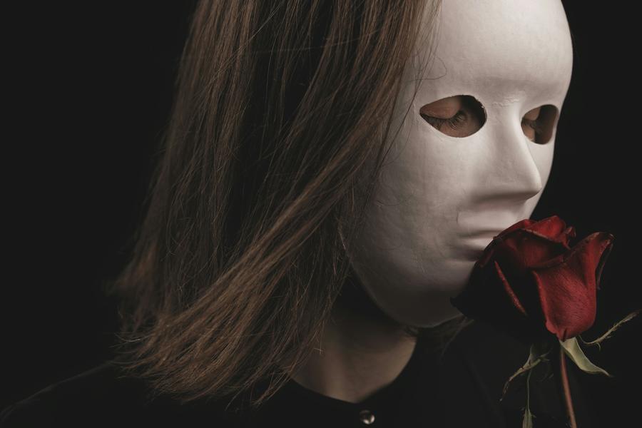 a lady with a mask holding a rose