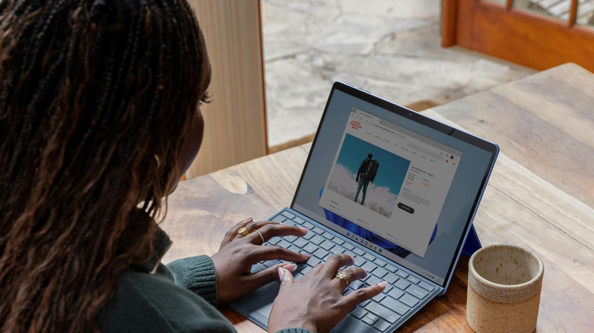 woman using a computer on a table with a mug next to the laptop