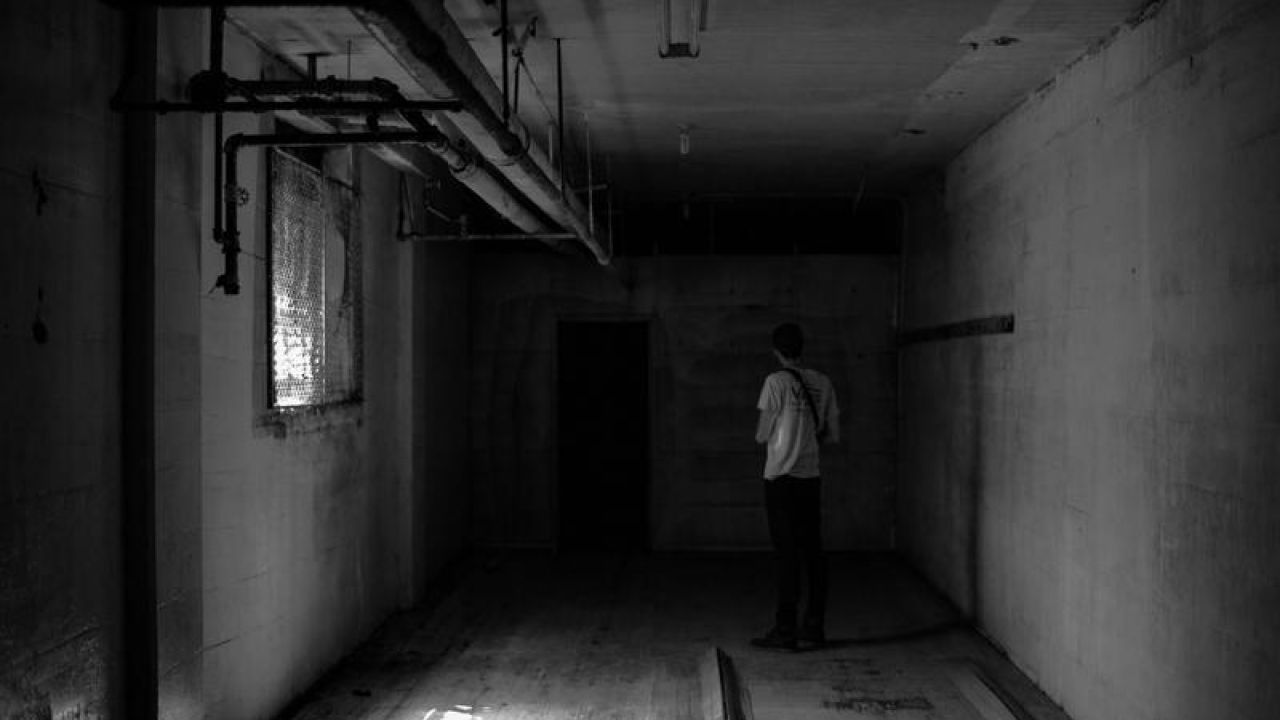 Man facing a dark door in a basement
