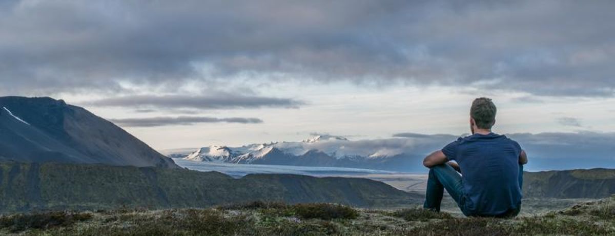 Man looking out to horizon mountains