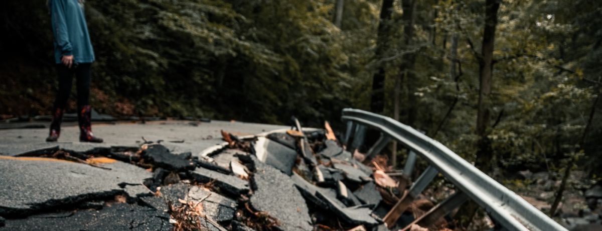 woman looking down at a broken asphalt road