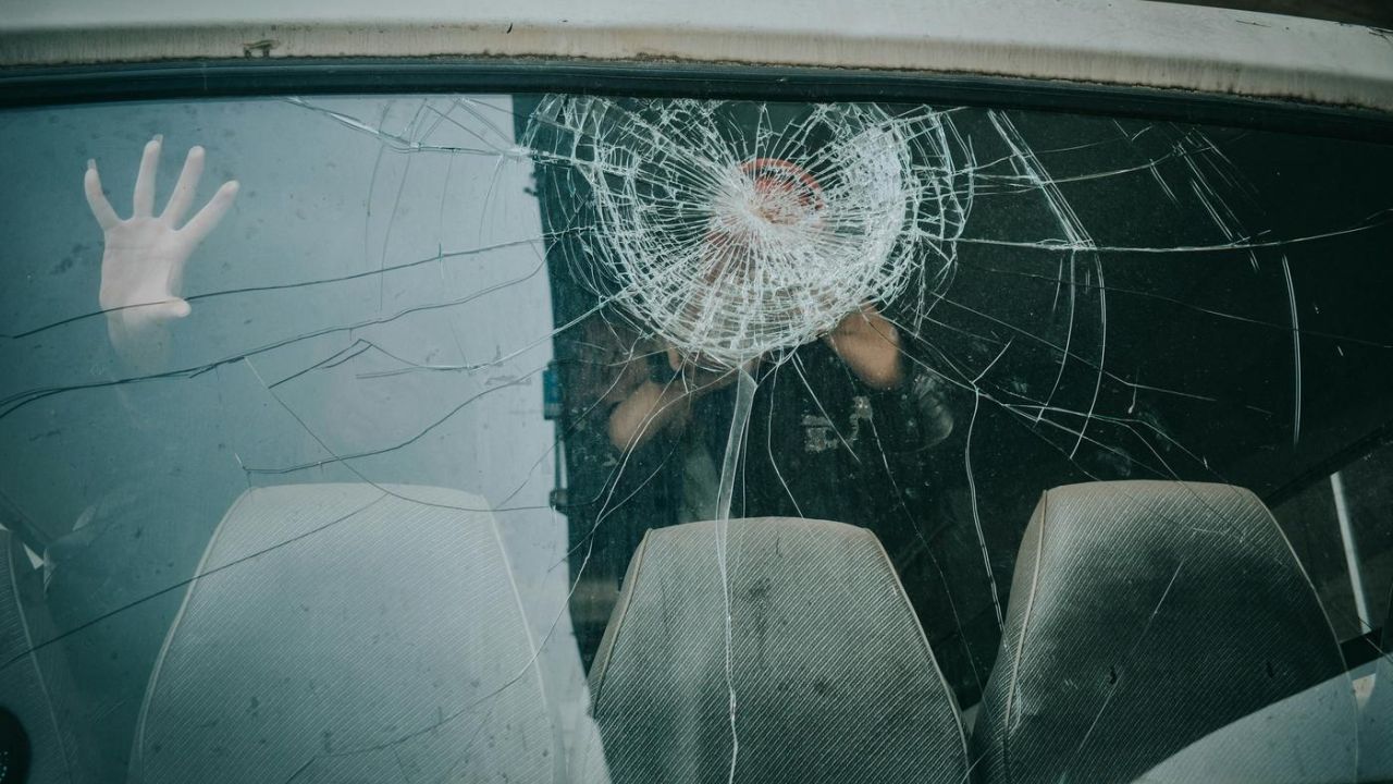 hand inside car on cracked windshield