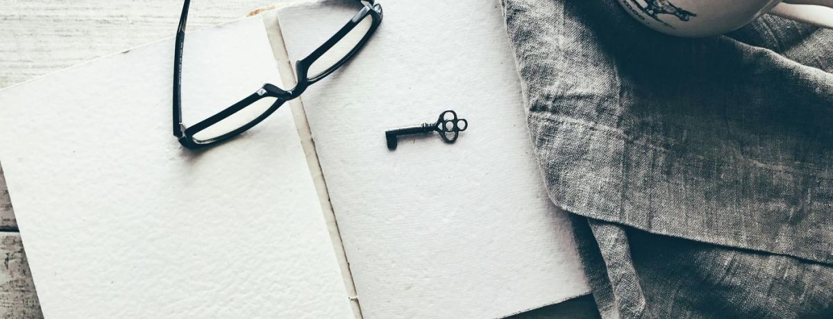 key and glasses on a note pad on a desk indoors