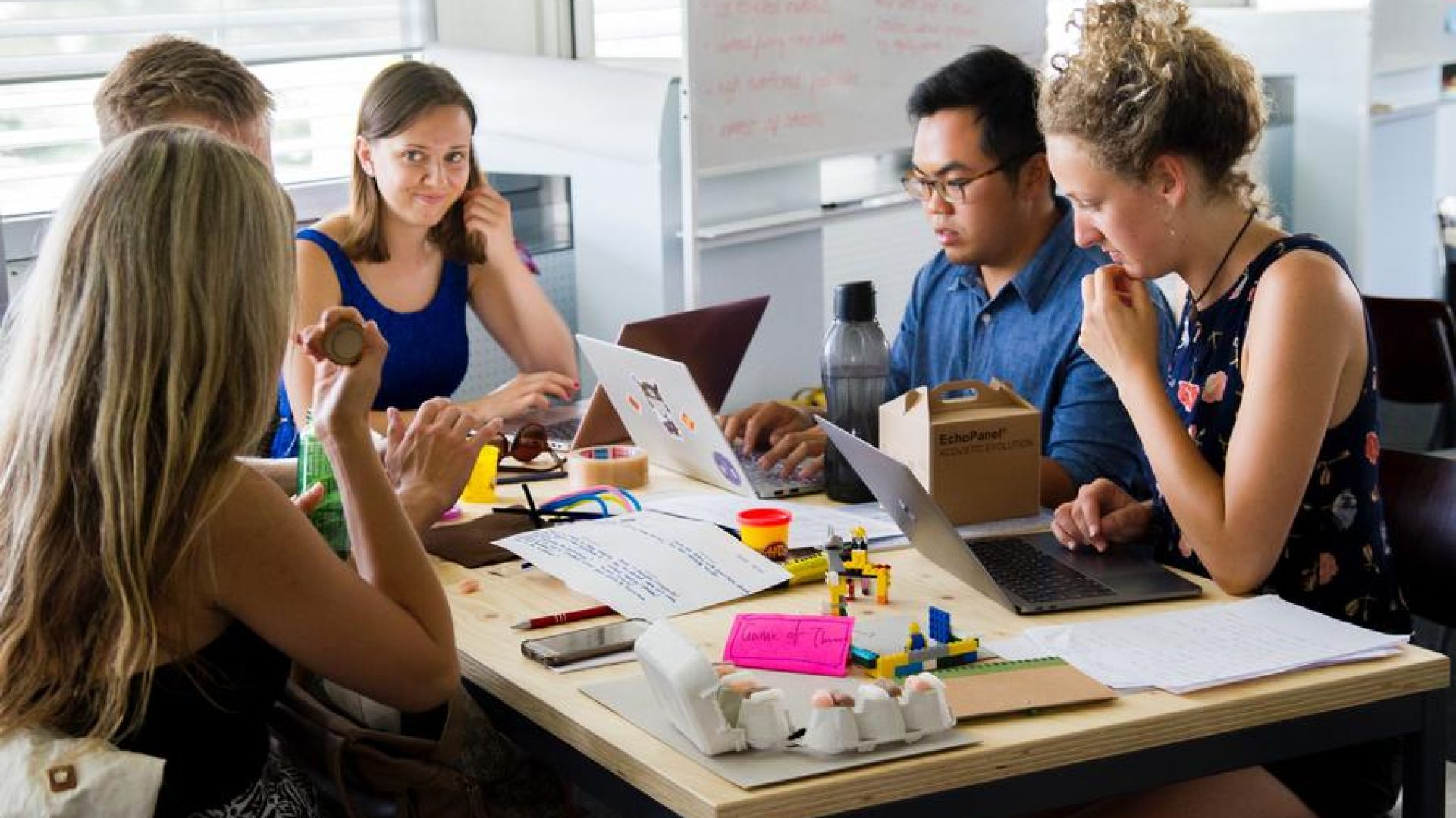 A Team Of People Sitting Around A Table Working