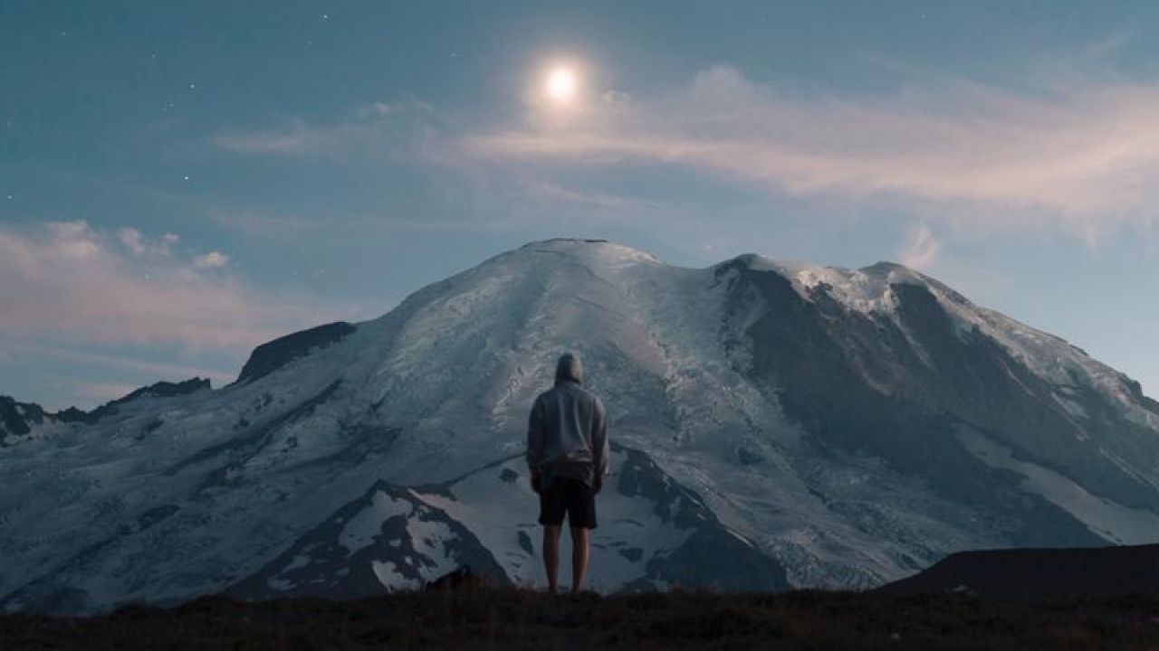 man looking up at mountain