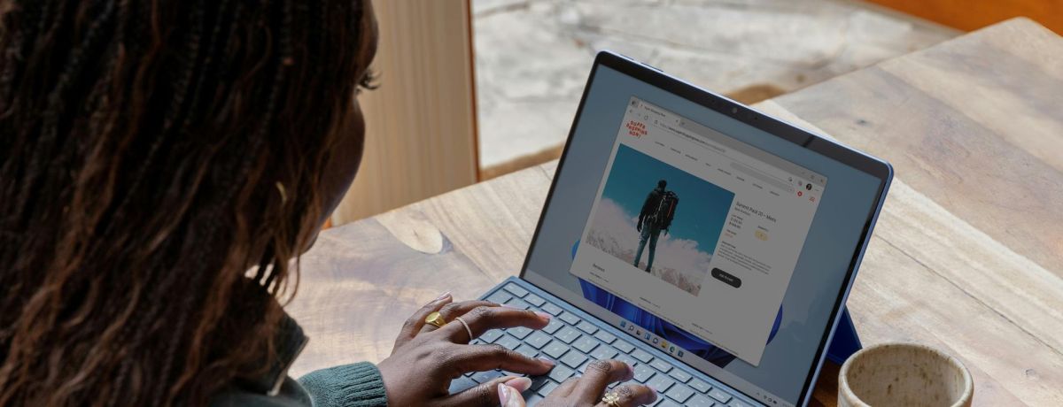 woman using a computer on a table with a mug next to the laptop