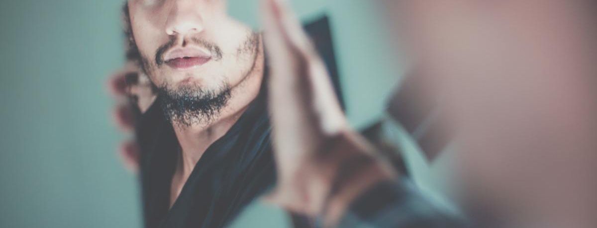 a man looking into a broken piece of a mirror