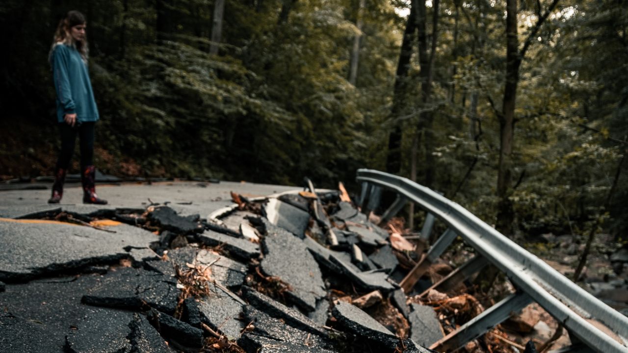 woman looking down at a broken asphalt road