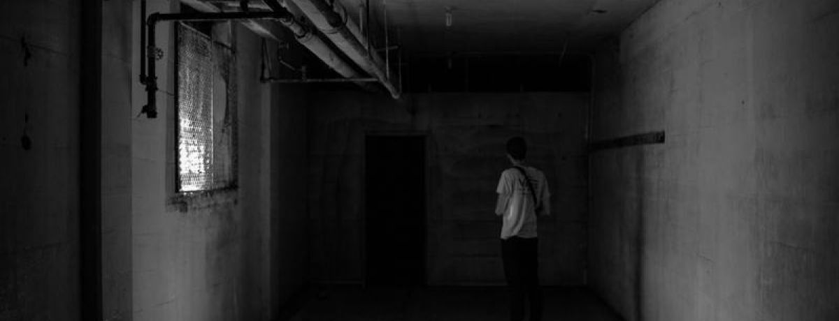 Man facing a dark door in a basement