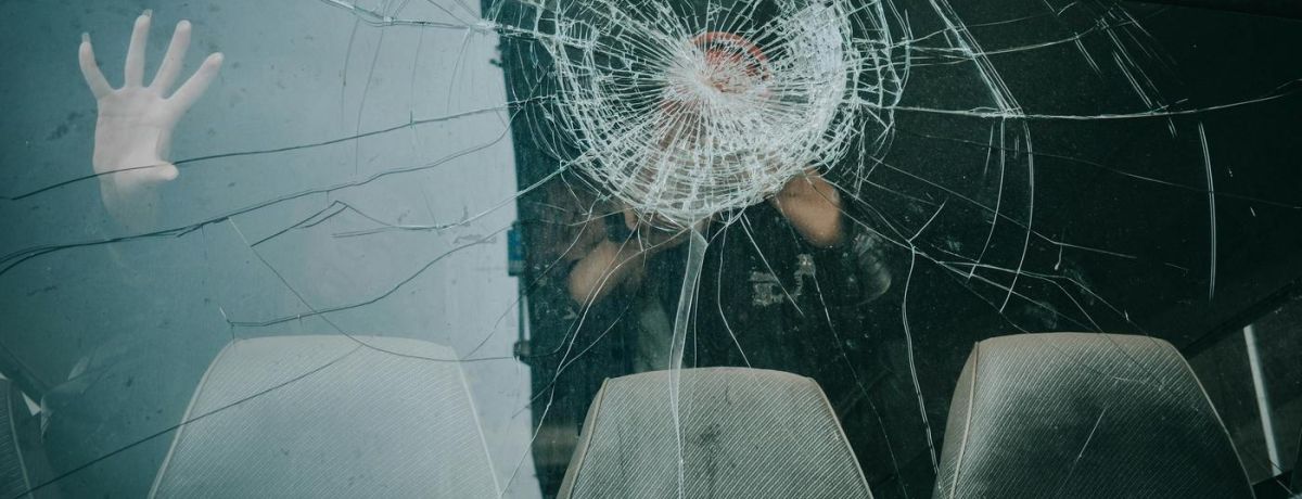 hand inside car on cracked windshield
