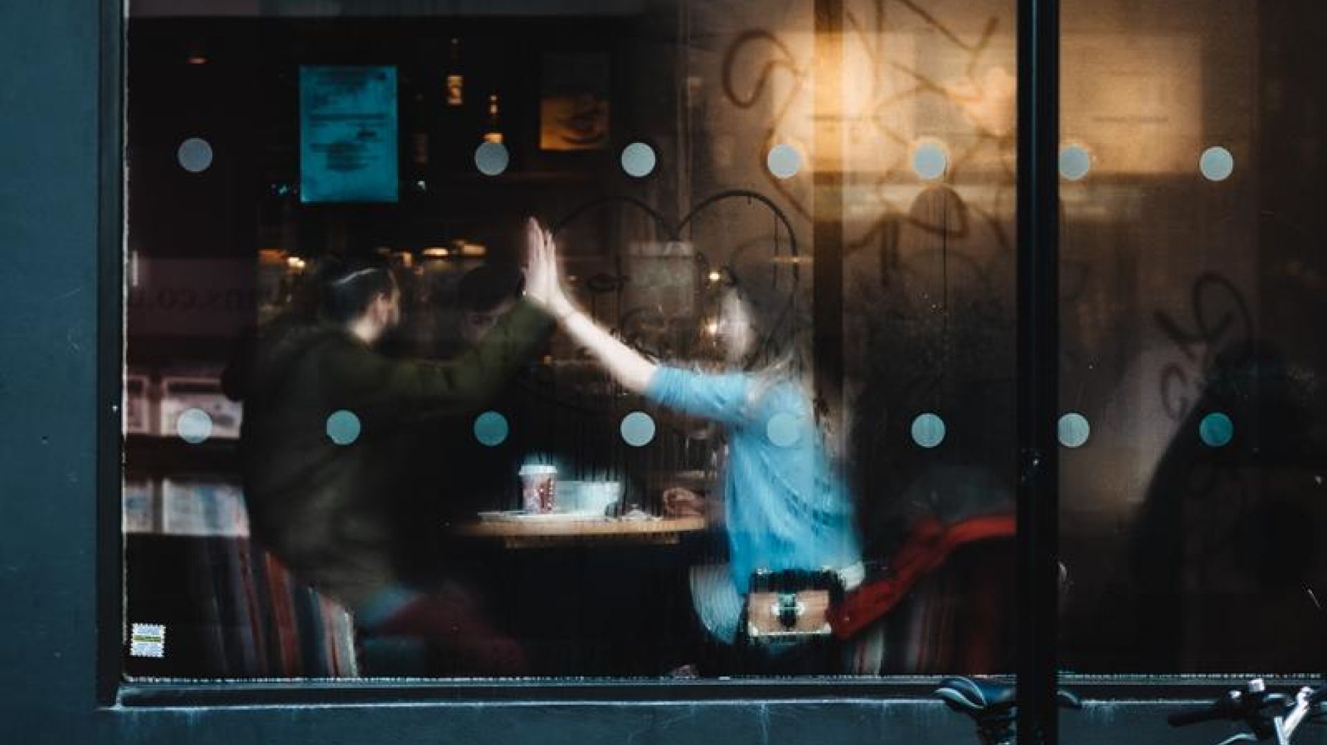 two people high fiving inside a coffee shop