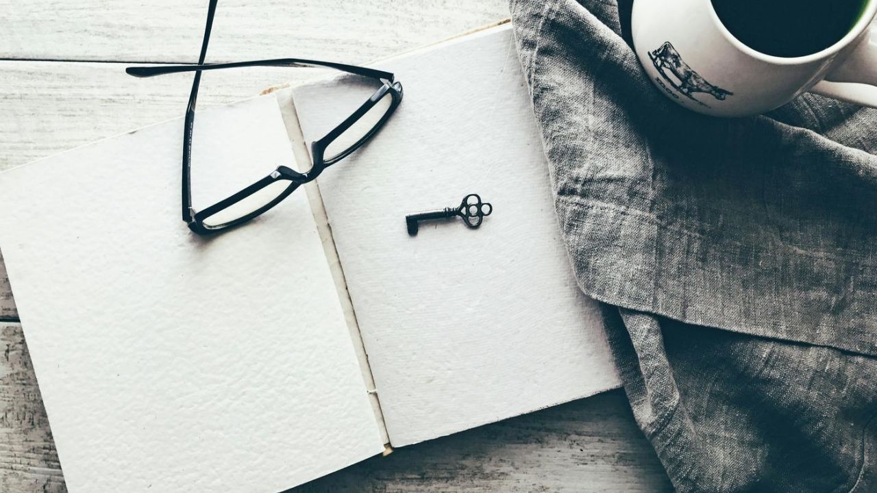 key and glasses on a note pad on a desk indoors