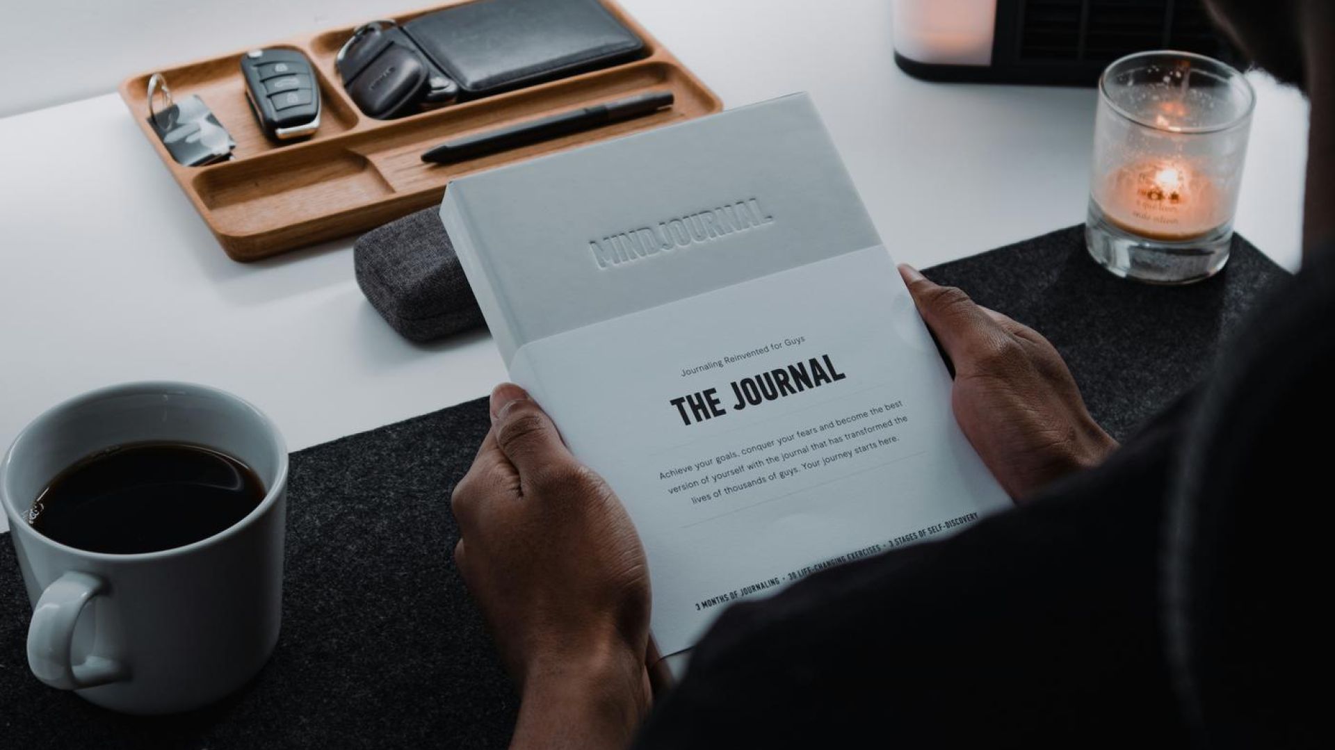 person sitting at a desk, drinking and journaling