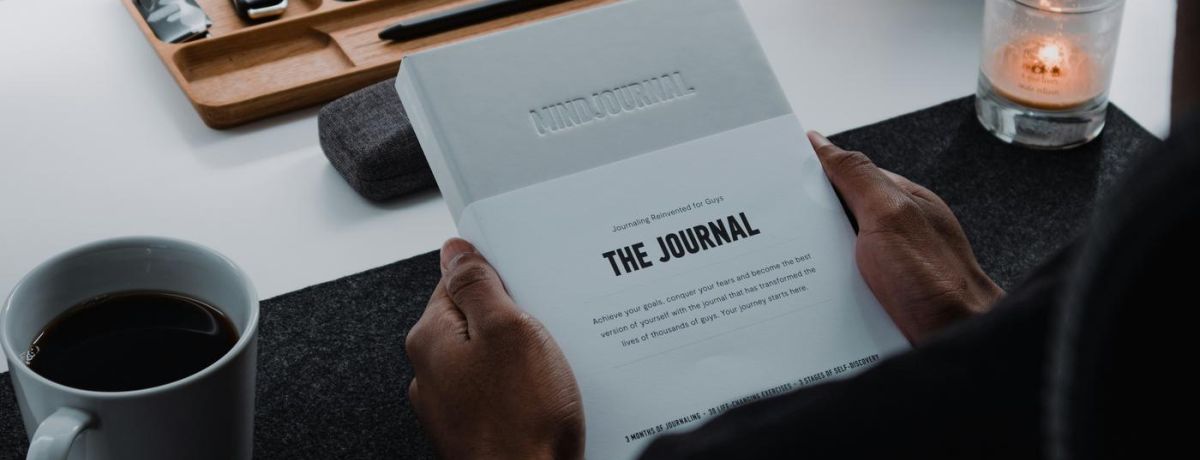 person sitting at a desk, drinking and journaling