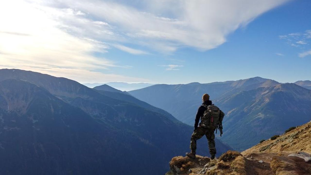 adventure: man standing on the edge of a cliff looking out at the mountains