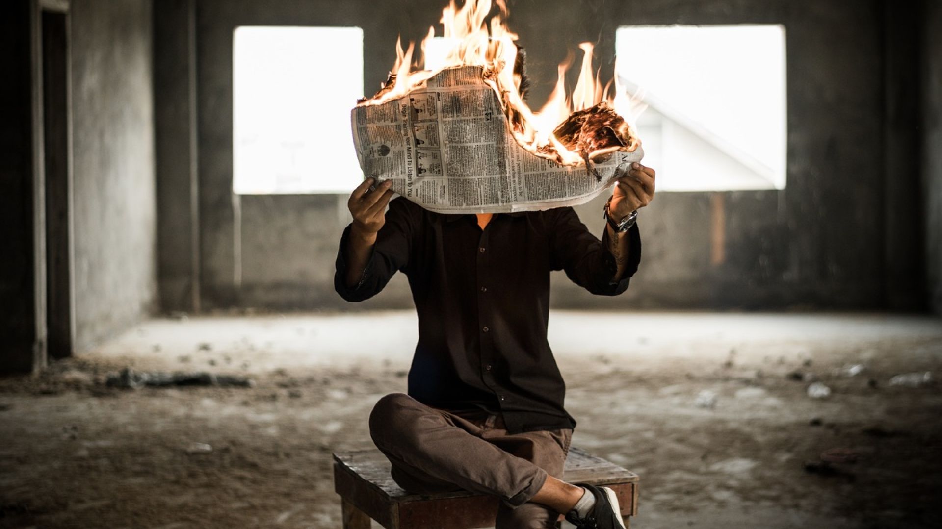 man holding a burning newspaper