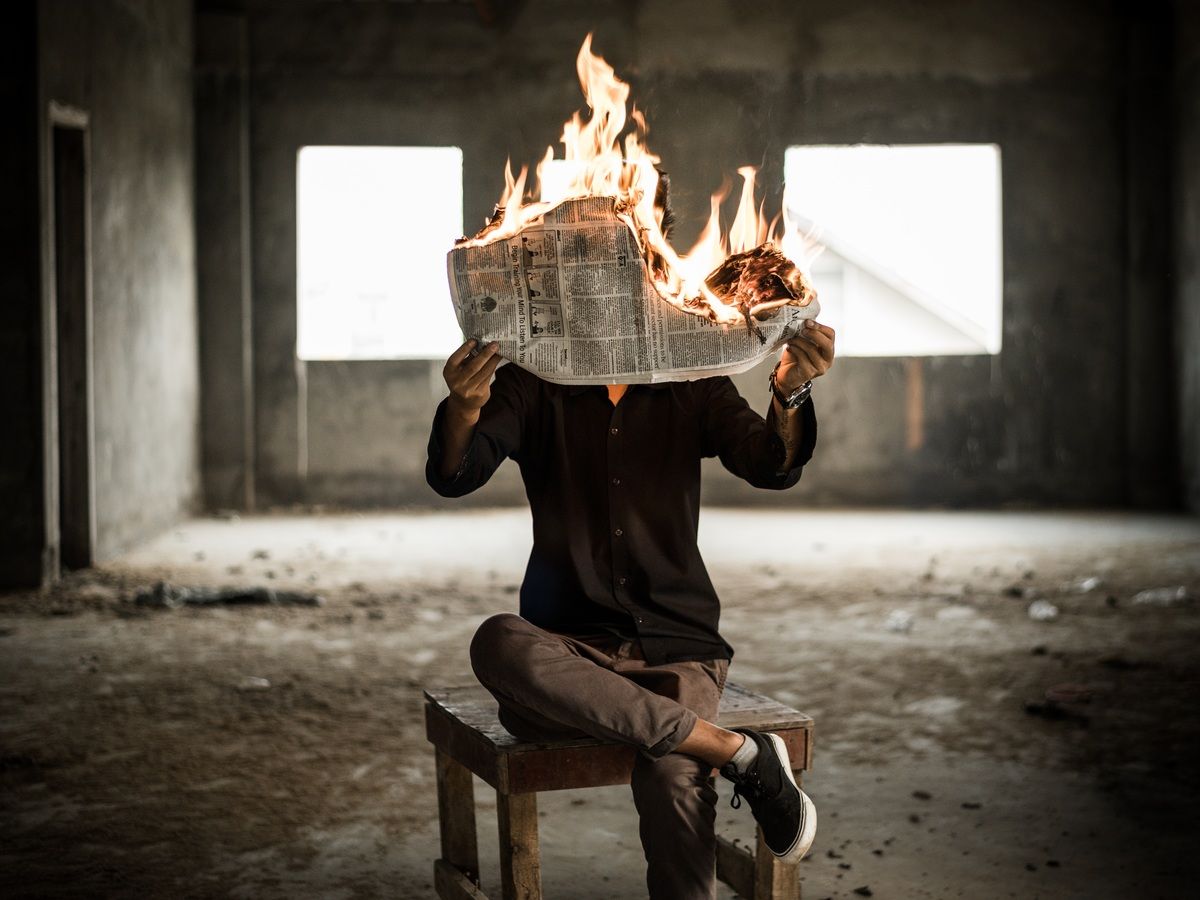 man holding a burning newspaper