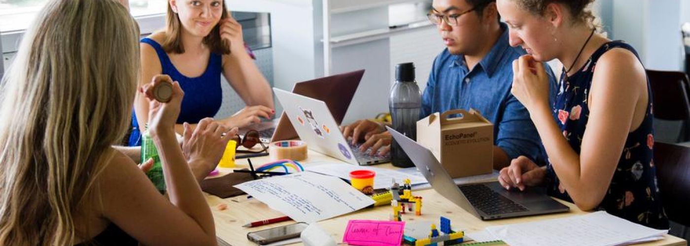 A Team Of People Sitting Around A Table Working