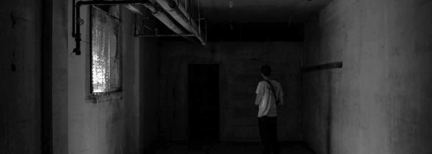 Man facing a dark door in a basement