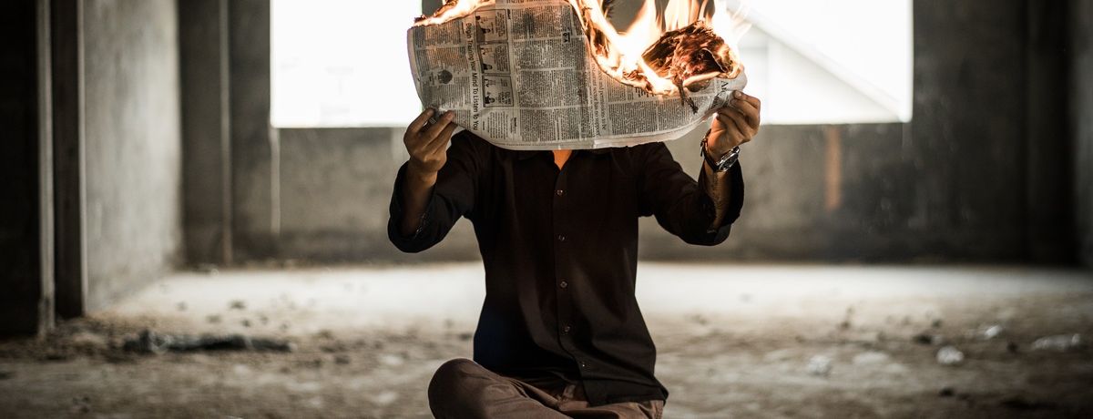 man holding a burning newspaper