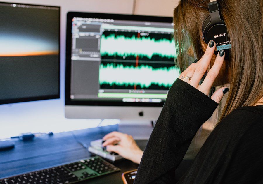 female audio editor with headphones working at desk in an indoors office
