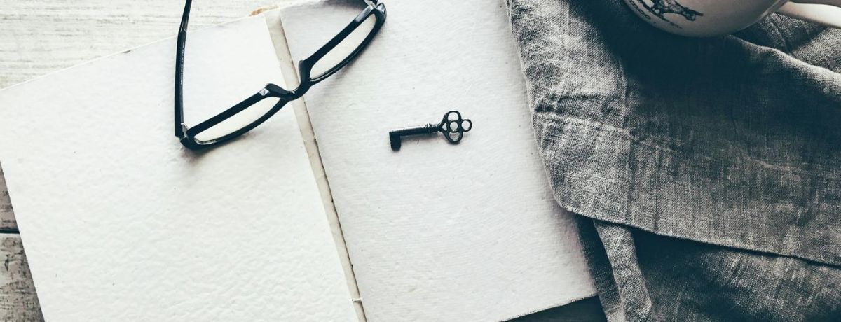 key and glasses on a note pad on a desk indoors