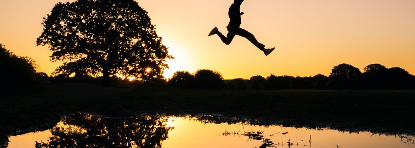 man jumping high across water