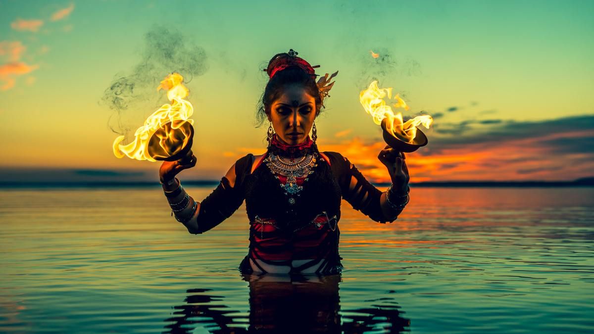 woman wiht fire cups in the water, outdoors