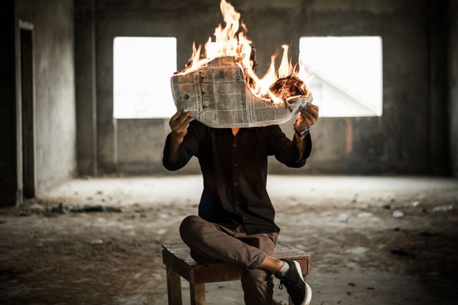 man holding a burning newspaper