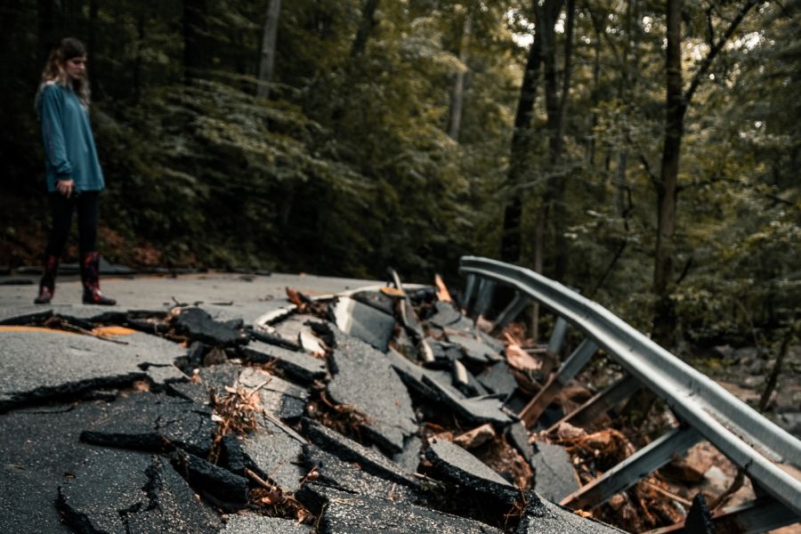 woman looking down at a broken asphalt road