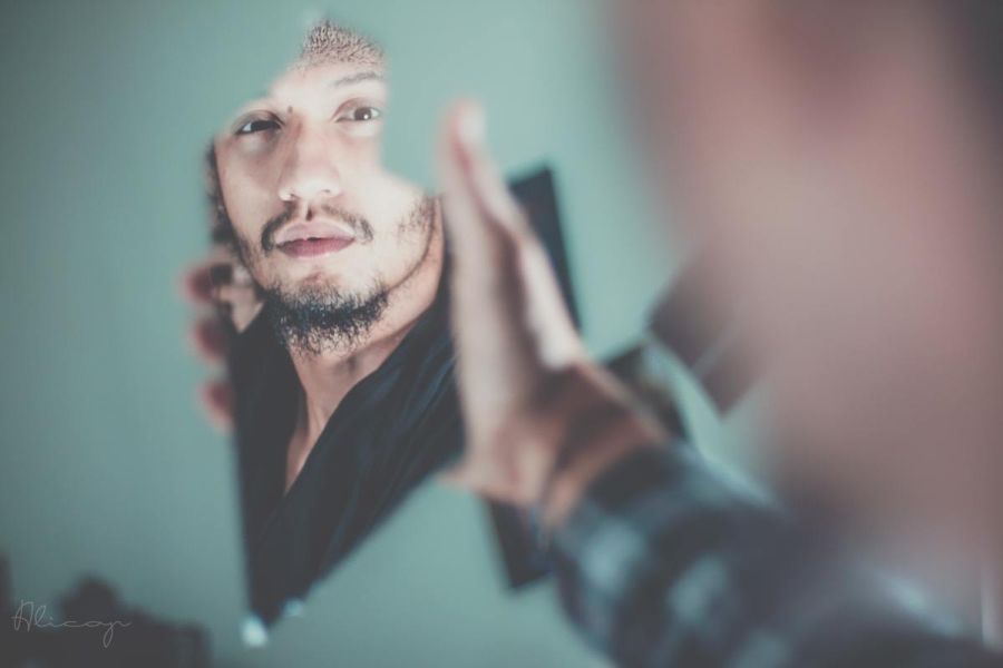 a man looking into a broken piece of a mirror