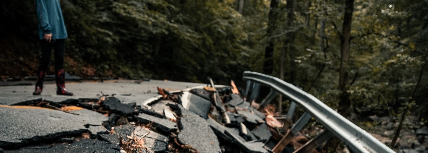 woman looking down at a broken asphalt road