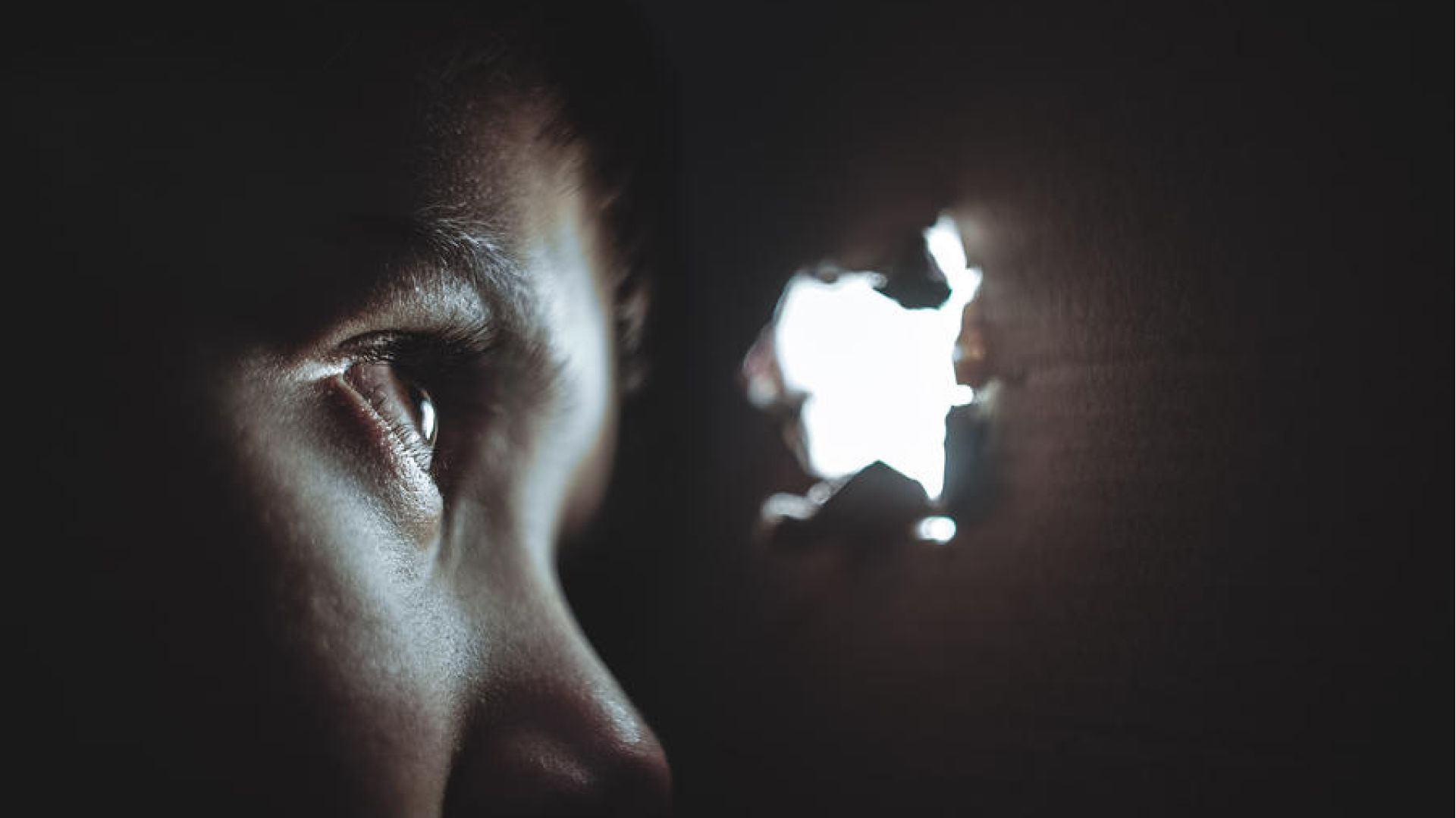person looking out a hole, light coming in