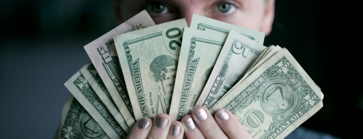 person, indoors, holding a fan full of money