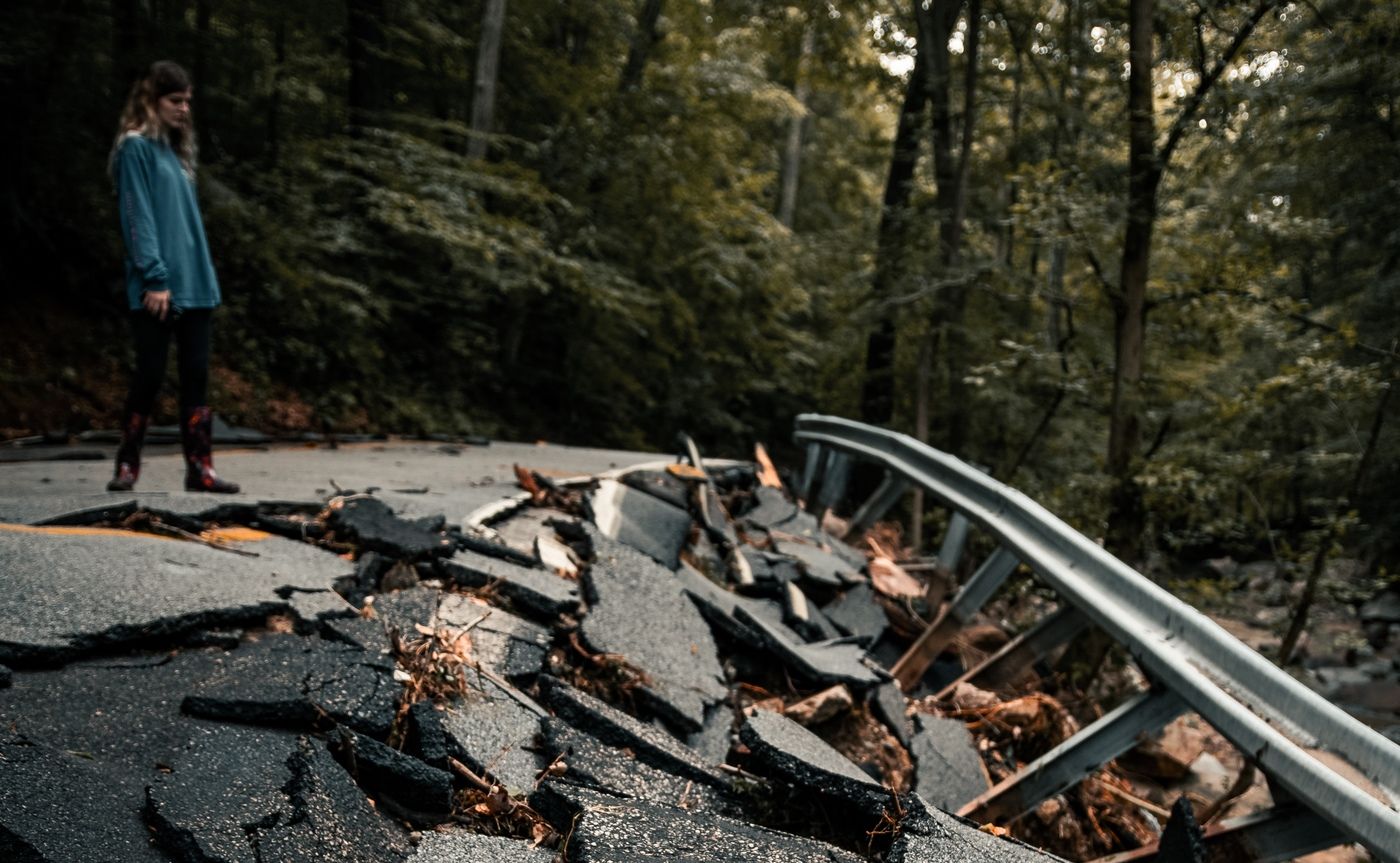 woman looking down at a broken asphalt road