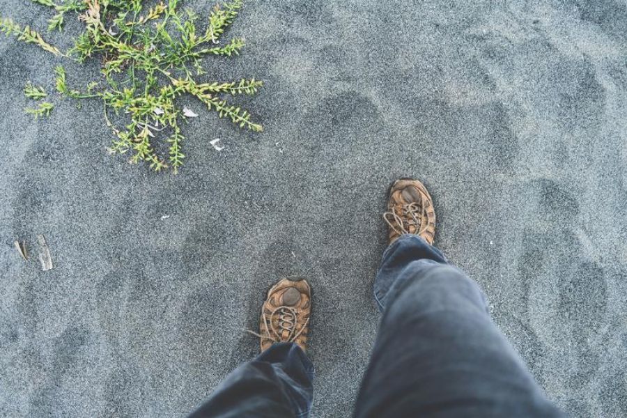 Steps onto sand, feet view