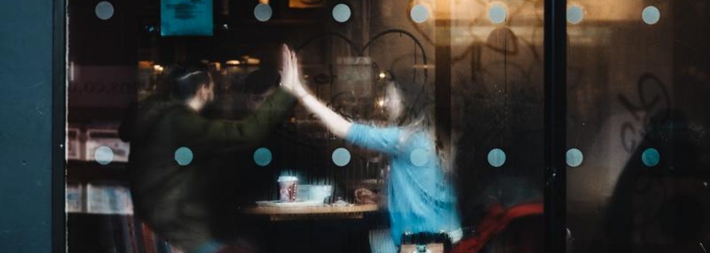 two people high fiving inside a coffee shop